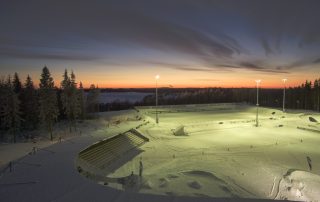 Auringonlasku talvisen pesäpallostadionin takana