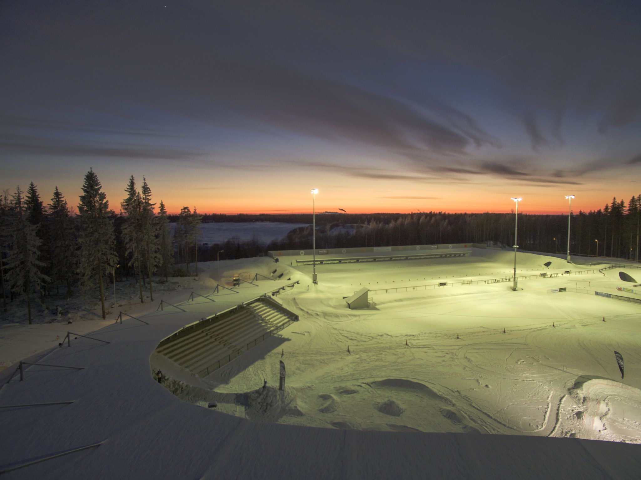 Auringonlasku talvisen pesäpallostadionin takana